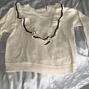 THE GREAT. Cream Textured Knit Sweater V
Ruffle with black Rickrack trim. Size 1